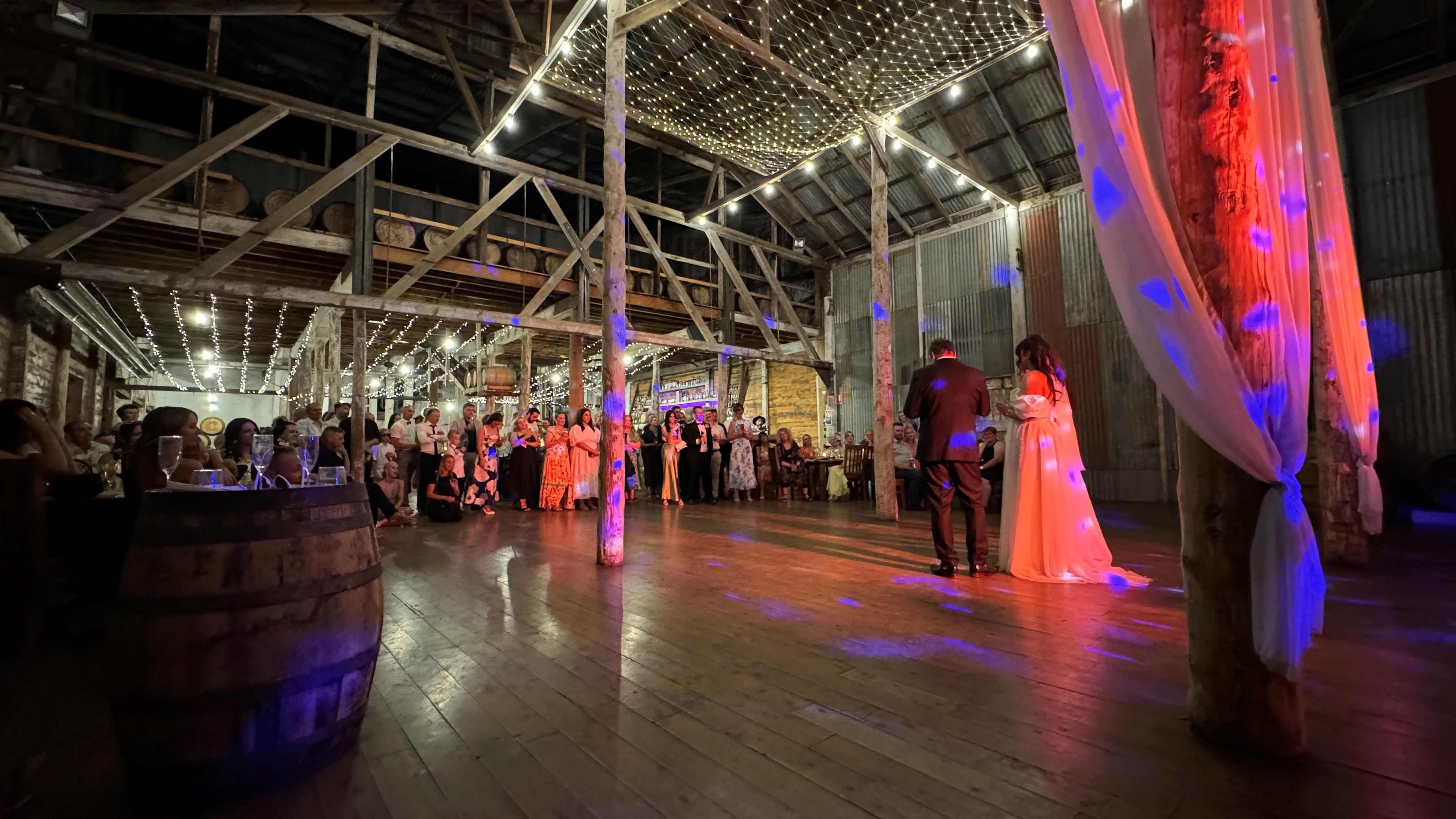 Couple's first dance with dramatic production lighting at rustic barn wedding reception