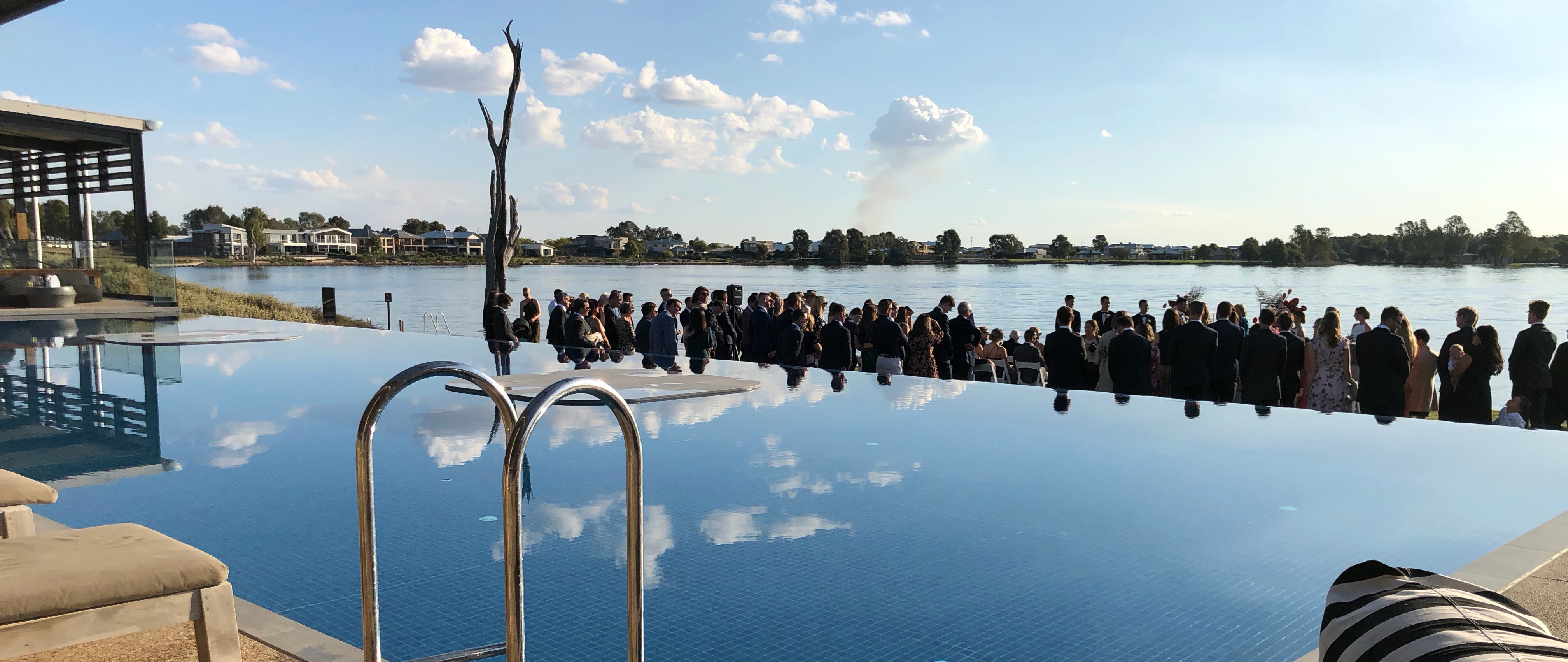 Outdoor wedding ceremony at waterfront venue with guests seated