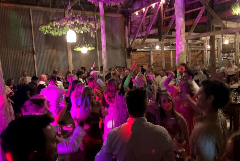 Packed dancefloor under pink party lighting at a Melbourne wedding reception