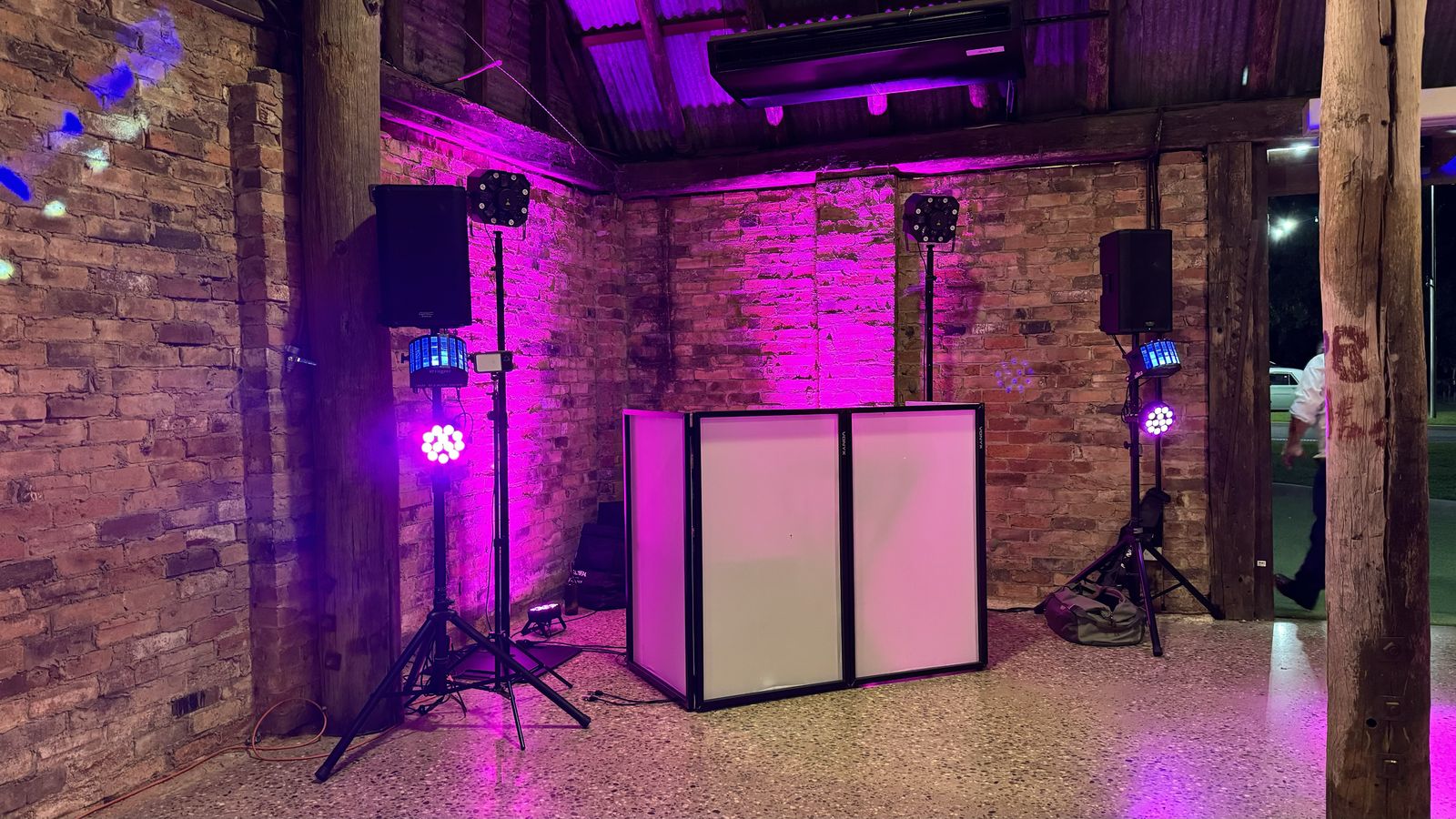 DJ booth with pink uplighting in an exposed-brick reception room