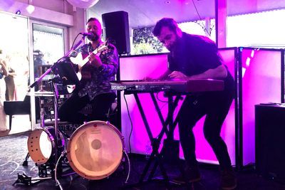 Live duo on keys and drums under pink production lighting