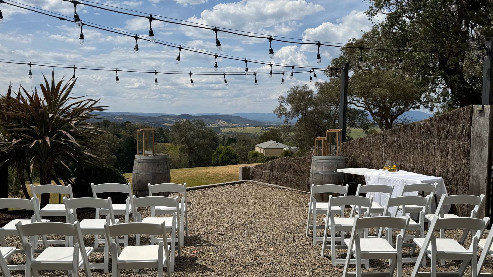 Ceremony chairs under festoon lights overlooking vineyard hills