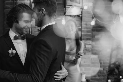 Two grooms embracing during their first dance, black and white