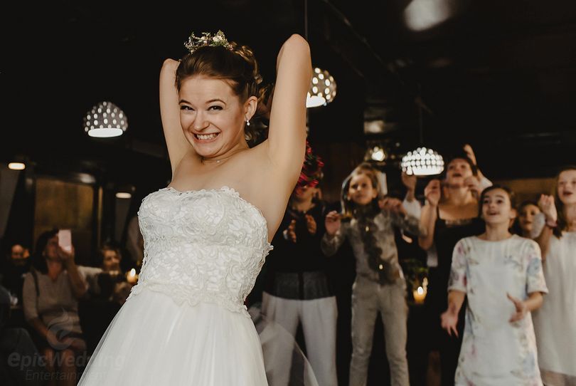 Bride celebrating with arms raised on the dancefloor